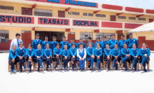 a group of students are posing for a photo in front of a building that says studio trabajo disciplina