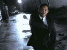 a man in a suit and tie is walking down a wet street .