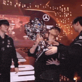 a man holding a trophy with a mercedes logo on it