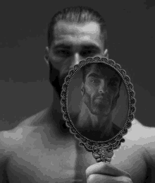 a man without a shirt is looking at his reflection in a hand mirror