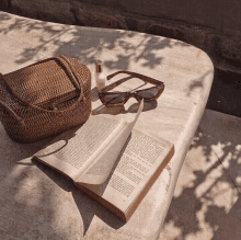 a wicker bag sunglasses and a book are on a table outside