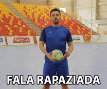 a man in a blue shirt holds a soccer ball in front of an empty stadium with the words fala rapaziada below him