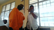 a man in an orange shirt stands next to a man in a white shirt