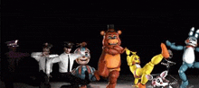 a group of five nights at freddy 's characters are dancing in a dark room .