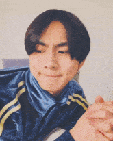 a young man wearing a blue jacket with yellow stripes on the sleeves is making a funny face