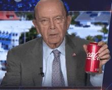 a man in a suit and tie holds a red can of coca cola