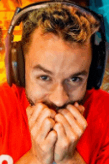 a man with a beard wearing headphones is covering his mouth with his hands .