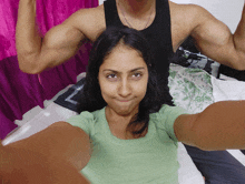 a woman taking a selfie with a man flexing his muscles in the background