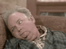 a man is laying on a couch making a funny face .