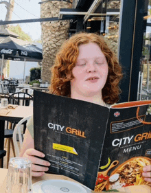 a girl with red hair is reading a menu for city grill