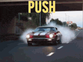 a red car is driving under a bridge with the word push on it