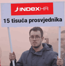 a man is holding a sign that says indexhr