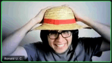 a man wearing a straw hat and glasses is on a video call with ronald u c.