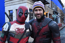 a man in a deadpool costume stands next to another man in a beanie