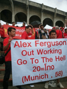 a group of people holding a banner that says alex ferguson out working go to the hell