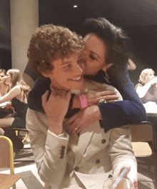 a woman kisses a young man on the cheek while sitting at a table