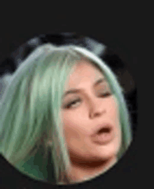 a close up of a woman with green hair making a funny face .