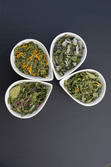 four white bowls filled with different types of herbs and flowers