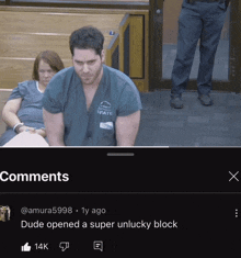 a man in a state scrub is sitting in a courtroom with a woman behind him