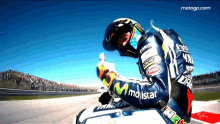 a motorcycle racer wearing a jacket that says ' movistar ' on it