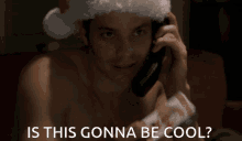 a shirtless man wearing a santa hat talking on a cell phone