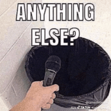 a person is holding a microphone in front of a trash can that says anything else ?
