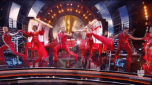 a group of people are dancing on a stage with a clock in the background and the letters nbc on the bottom