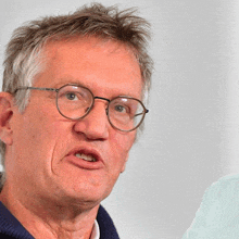 a close up of a man wearing glasses and a blue sweater