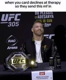 a man is sitting in front of a ufc belt