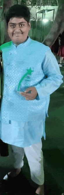 a young boy wearing a blue jacket and white pants is holding a green trophy .