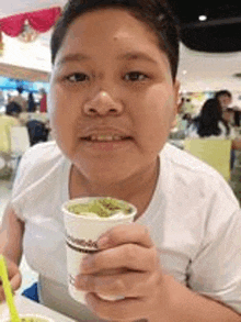 a young boy is holding a cup of ice cream and eating it .