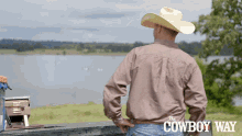 a man wearing a cowboy hat and a shirt that says the cowboy way looks out over a body of water