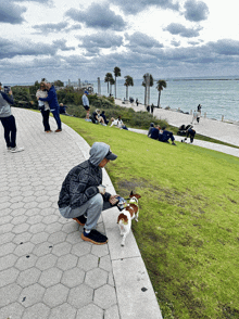 a man kneeling down with a dog on a leash in front of the ocean