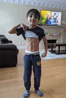 a young boy flexes his muscles in front of a tv screen showing a family