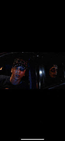 a man wearing a bandana and a woman wearing a mask are sitting in a car at night