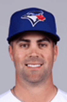 a baseball player wearing a blue jays hat is smiling .