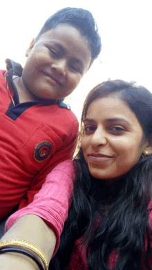 a boy wearing a red shirt with a patch that says ' army ' on it poses for a picture with a woman