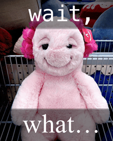 a pink stuffed animal is sitting in a shopping cart with the words wait what on the bottom