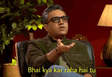 a man wearing glasses is sitting in a chair with the caption " bhai kya kar raha hai tu " above him