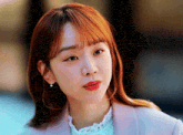 a close up of a woman 's face wearing earrings and a pink jacket