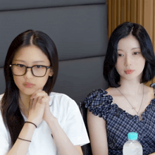 a girl wearing glasses sits next to a girl wearing a plaid top