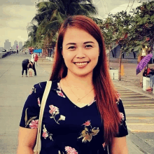 a woman wearing a floral shirt and a necklace smiles for the camera