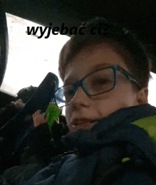 a young boy wearing glasses is sitting in a car with the words wyjebac ci written on the bottom