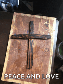 a wooden cross sits on a wooden board under the words peace and love