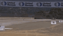 a race car is going down a track with united rentals banners behind it