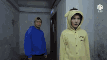 a man in a blue hoodie and a woman in a yellow hoodie are standing next to each other ..