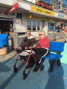 two people sitting on a bench in front of a pizza cannoli restaurant