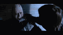 darth vader is holding a person 's hand in front of his face .