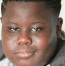 a close up of a young boy 's face with a gray shirt on .