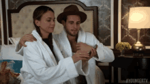 a man and a woman in bathrobes are looking at a cell phone with the hashtag #youngertv